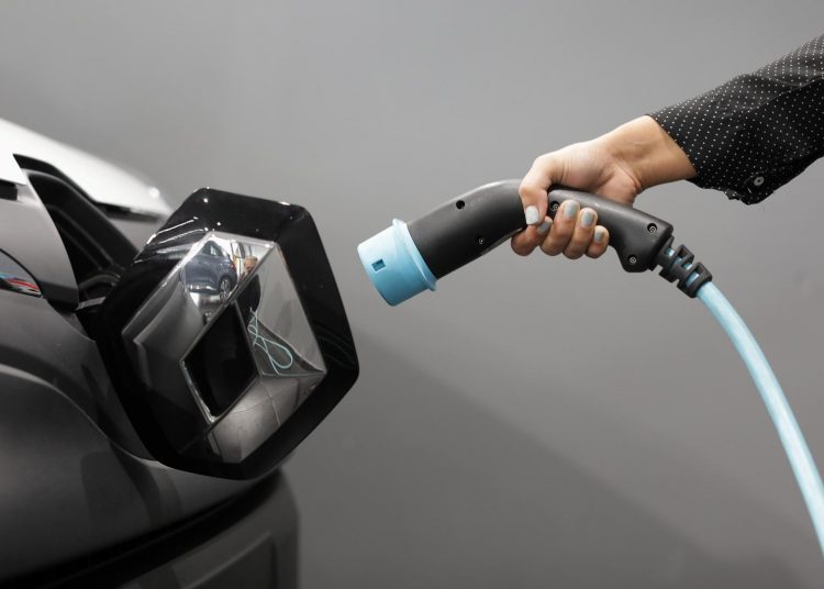 FILE PHOTO: A woman holds a cable to charge up a Renault Kangoo ZE electric utility vehicle at a Renault automobile dealership in Cagnes-Sur-Mer, France, October 22, 2020.