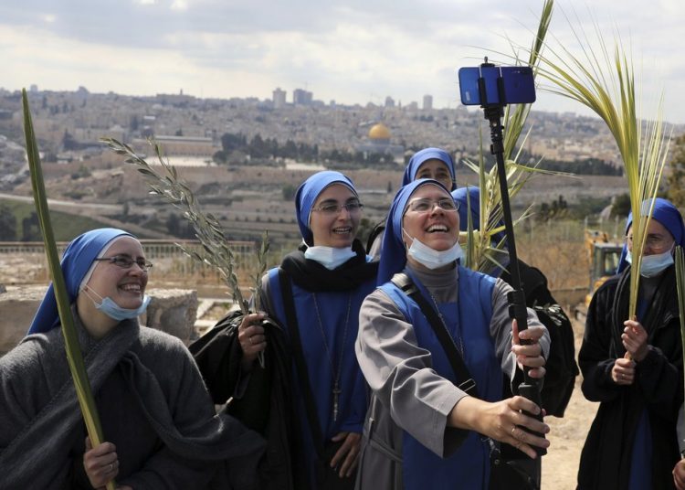 Nuns pose for a selfie as they mark Palm Sunday on the Mount of Olives in Jerusalem, Sunday, March 28, 2021. A year after coronavirus restrictions halted mass gatherings, Christians are celebrating Holy Week together