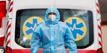 A medical worker wearing protective gear standing next to an ambulance outside a hospital for patients infected with Covid-19 in Kyiv, Ukraine.
