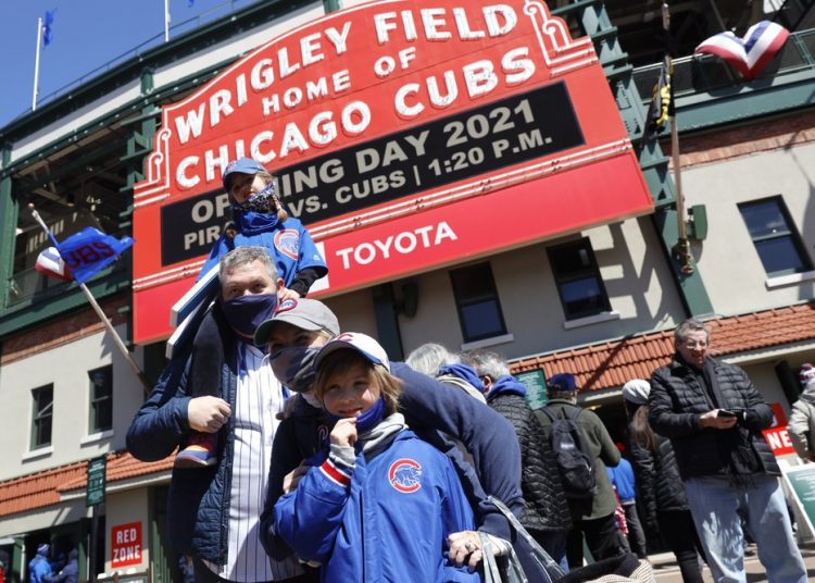 A family poses for a photo outside of Wrigley Field on the opening day baseball game between the Chicago Cubs and the Pittsburgh Pirates, Thursday, April 1, 2021, in Chicago. From New York to Seattle and everywhere in between, it is a much different opening day in 2021. Fans are back at the ballpark after they were shut out during the regular season last year because of the coronavirus pandemic