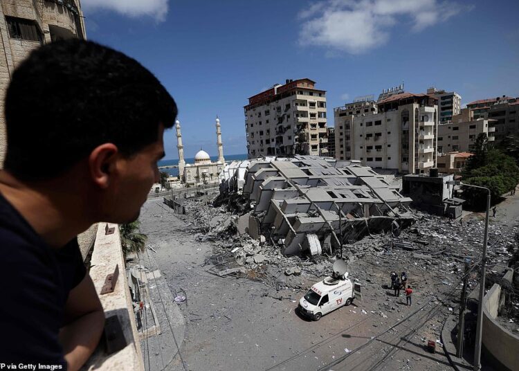 A Palestinian man looks out at a destroyed tower block in Gaza this morning following a night of heavy bombardments by the Israeli Air Force