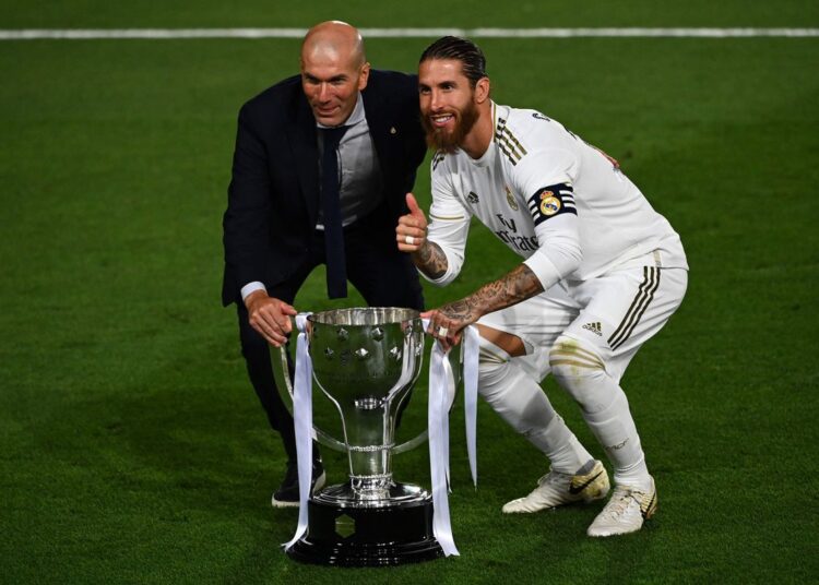 Real Madrid coach Zinedine Zidane (L) and defender Sergio Ramos celebrate with the trophy after winning the La Liga title, on July 16, 2020.