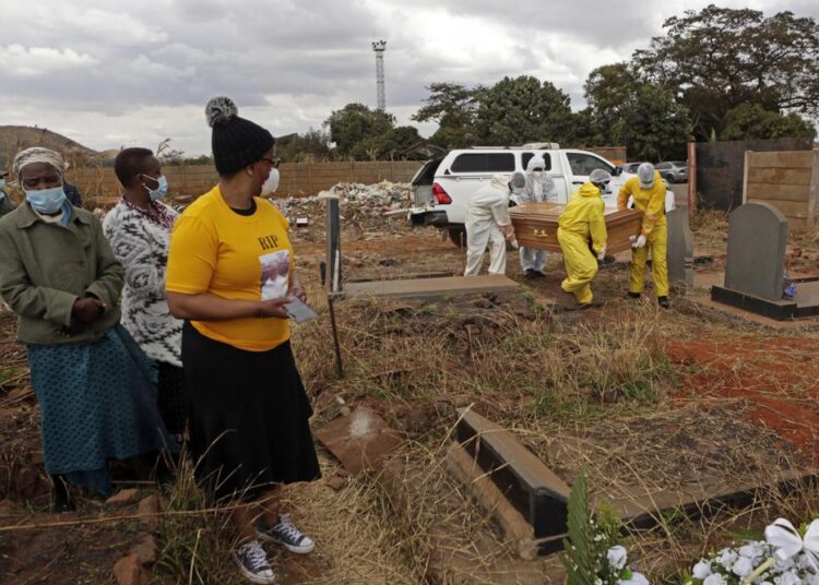 A family watches pallbearers carry the coffin of a relative who died from COVID-19 at a cemetery in Harare, Zimbabwe on Thursday, July 15, 2021. Only about 9% of the population in Zimbabwe has received one dose of coronavirus vaccine.