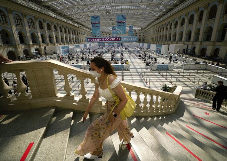 A woman climbing the stairs to queue for a COVID-19 vaccine at a vaccination center in Gostiny Dvor, a huge exhibition center, in Moscow, Russia, Tuesday, July 13, 2021. The banner, center, reads "We will defeat COVID-19 together!". Russia gave Sputnik V regulatory approval in August 2020, raising criticism at home and abroad because it had only been tested on a few dozen people at the time.