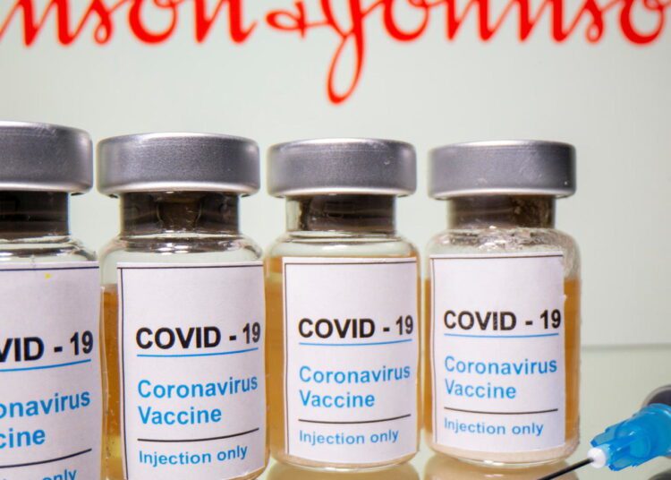 Vials labelled "Covid-19 Coronavirus Vaccine" and sryinge are seen in front of displayed Johnson&Johnson logo in this illustration taken, February 9, 2021.