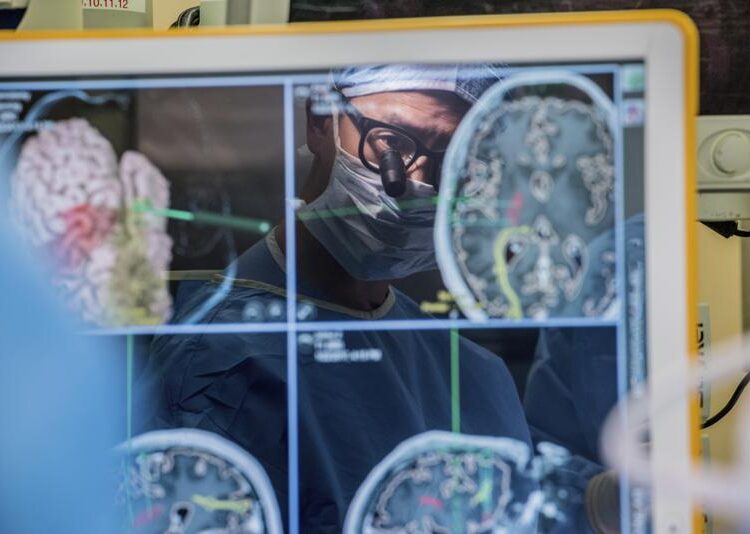 Device taps brain waves to help paralyzed man communicate 1 - Egyptian Gazette In this 2017 photo provided by the University of California, San Francisco, neurosurgeon Dr. Edward Chang is reflected in a computer monitor displaying brain scans as he performs surgery at UCSF. In a medical first, researchers, led by Chang, harnessed the brain waves of a man paralyzed and unable to speak for 15 years - and turned what he intended to say into sentences on a computer screen.