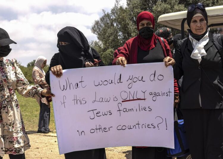 Israeli Arab women holding a sign during a protest ahead of a vote by Israel's parliament on renewing a law that bars Arab citizens of Israel from extending citizenship or even residency to spouses from the occupied West Bank and Gaza, outside the parliament building in Jerusalem, on Monday.