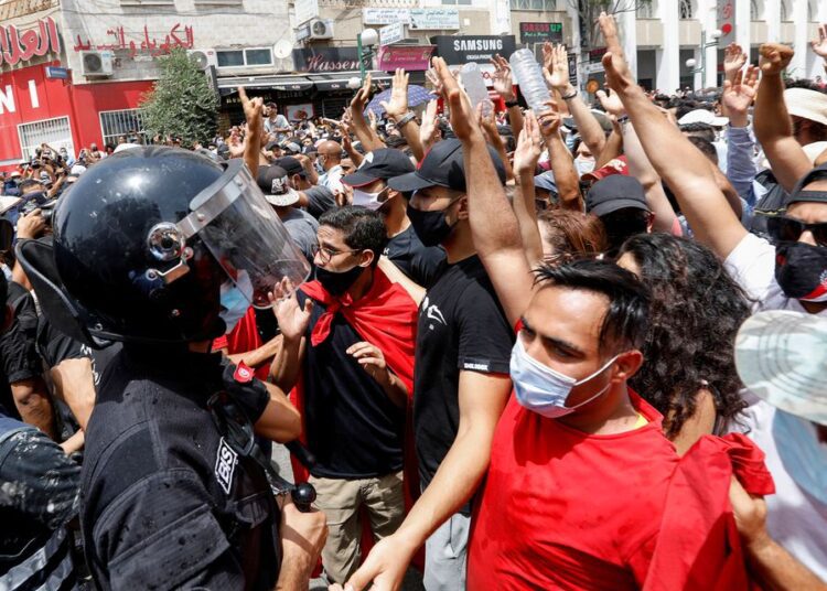 Demonstrators gathering in front of police officers standing guard during an anti-government protest in Tunis, Tunisia, Sunday.