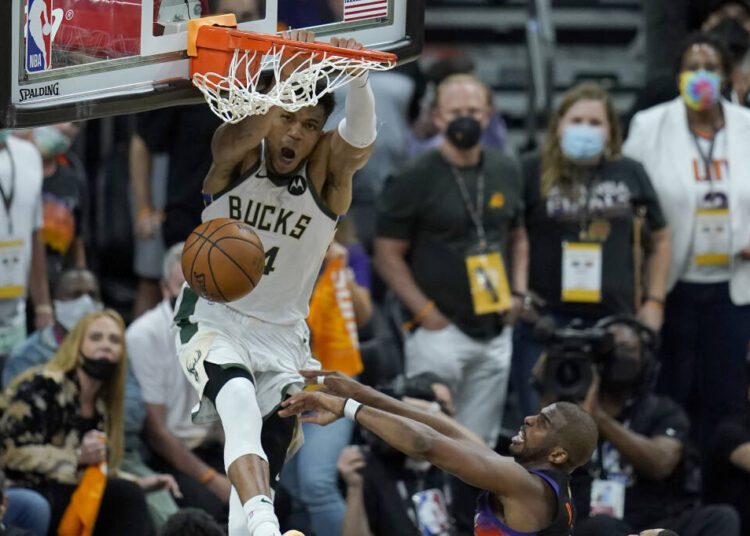 Milwaukee Bucks forward Giannis Antetokounmpo, top, dunks over Phoenix Suns guard Chris Paul during the second half of Game 5 of basketball's NBA Finals.