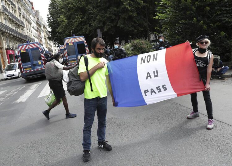 Two protestors hold the French flag with a message that reads "no to the pass" during a demonstration in Paris, France, Saturday, July 31, 2021