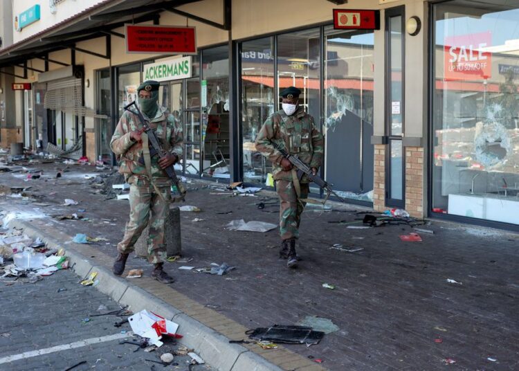Violence spreads in South Africa as grievances boil over 1 - Egyptian Gazette Members of the military patrol past looted shops as the country deploys army to quell unrest linked to jailing of former President Jacob Zuma, in Soweto, South Africa.