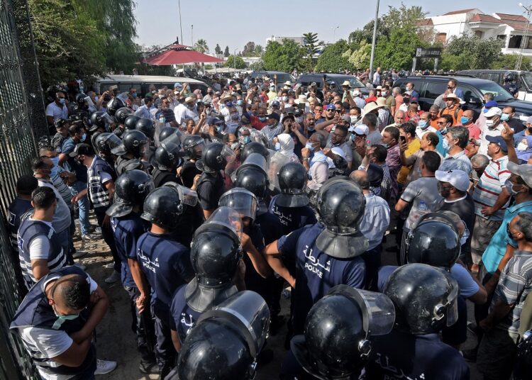 Clashes in Tunisia after president ousts PM amid Covid protests 1 - Egyptian Gazette Tunisian security officers hold back protesters outside the parliament building in the capital Tunis on Monday.