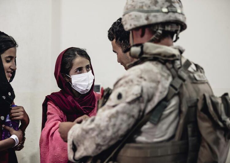 In this image provided by the U.S. Marine Corps, a Marine processes youth to be evacuated, at Hamid Karzai International Airport, Monday, Aug. 23.