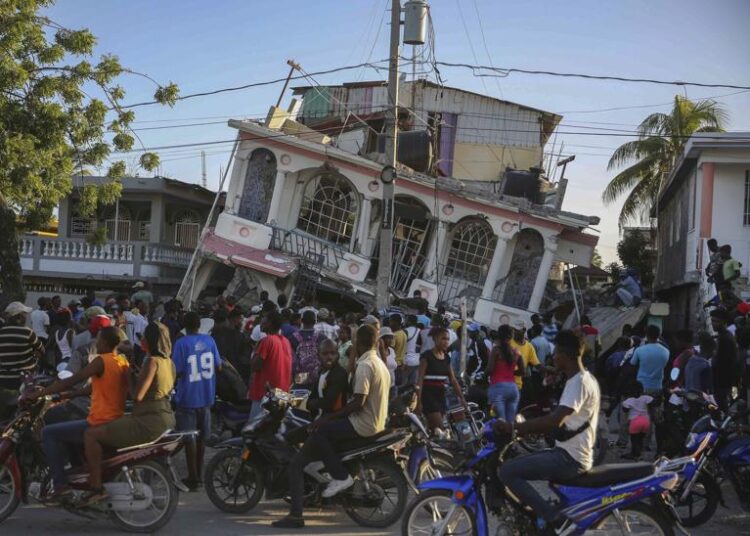 People gather outside the Petit Pas Hotel, destroyed by the earthquake in Les Cayes, Haiti, Saturday, Aug. 14, 2021. A 7.2 magnitude earthquake struck Haiti on Saturday, with the epicenter about 125 kilometers (78 miles) west of the capital of Port-au-Prince, the US Geological Survey said.