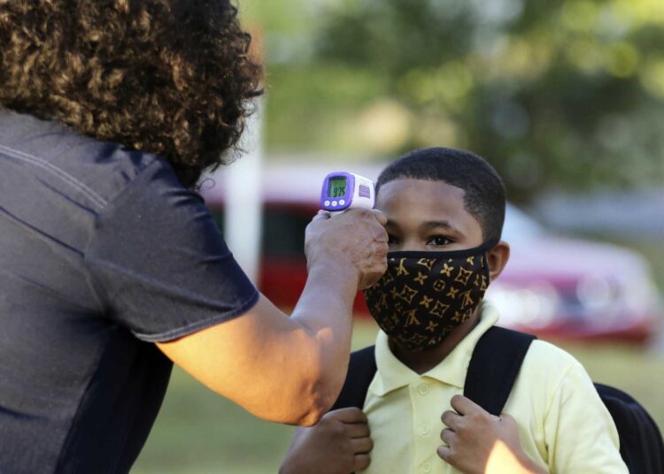 A file photo shows fifth-grader Marcques Haley, gets his temperature checked by school nurse Rachel White before entering Stephens Elementary School in Little Rock, Ark.