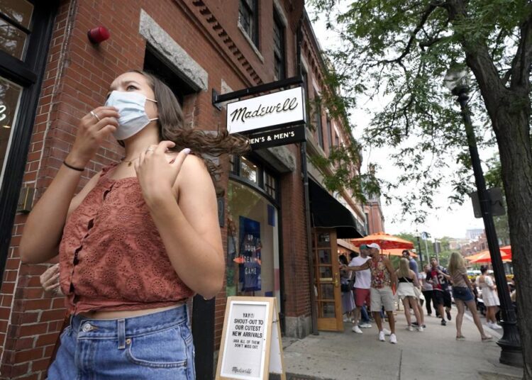 A pedestrian wears a mask out of concern for the coronavirus while walking along Boston's fashionable Newbury Street, on Aug. 8, 2021.