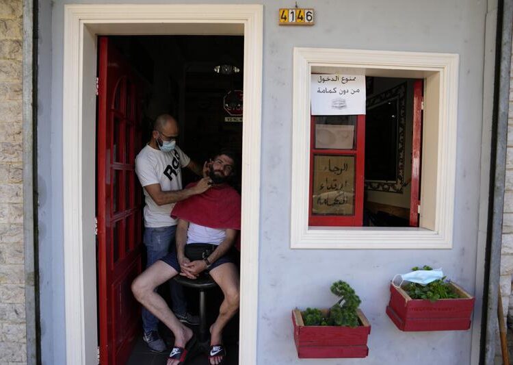 Anger in Lebanon over central bank ending of fuel subsidies 1 - Egyptian Gazette A Lebanese barber shaves the beard of a customer at the door of his shop during a power outage in a southern suburb of Beirut, Lebanon, Wednesday, Aug. 11, 2021. Lebanon, which is mired in multiple crises including a devastating economic crisis, has faced months of severe fuel shortages that have prompted long lines at gas stations and plunged the small country, dependent on private generators for power, into long hours of darkness. Sign on door says, "Forbidden to enter without mask."