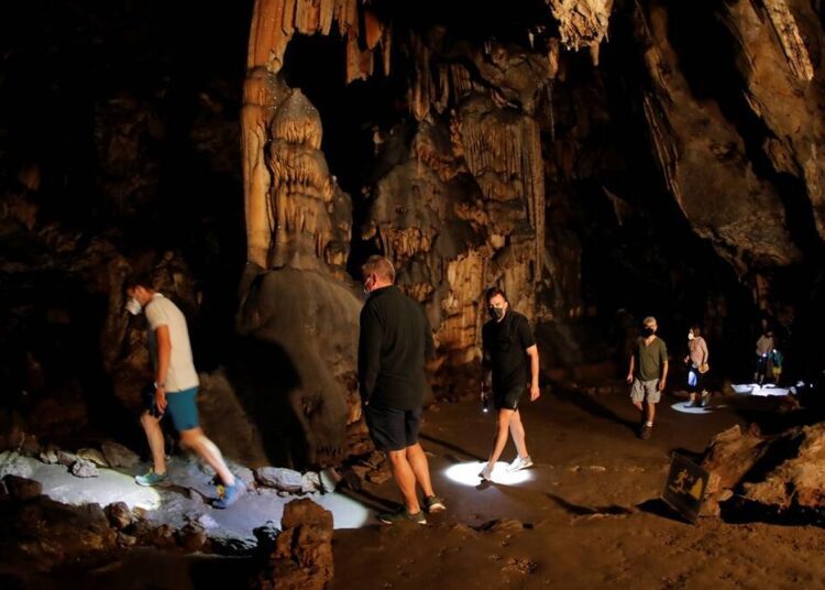 Visitors walk in the "Room of the Stars", in a prehistoric cave where red ocher markings were painted on stalagmites by Neanderthals about 65,000 years ago, according to an international study, in Ardales, southern Spain, on Saturday.