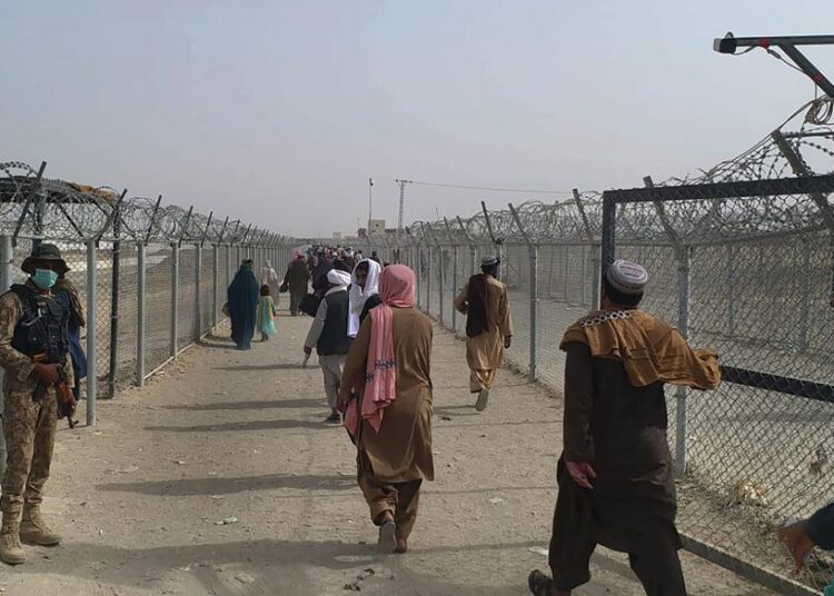Chaos as thousands flee Afghanistan after Taliban takeover 1 - Egyptian Gazette Pakistan soldiers stand guard while travelers cross the border to Afghanistan at a crossing point in Chaman, Pakistan, on Monday.