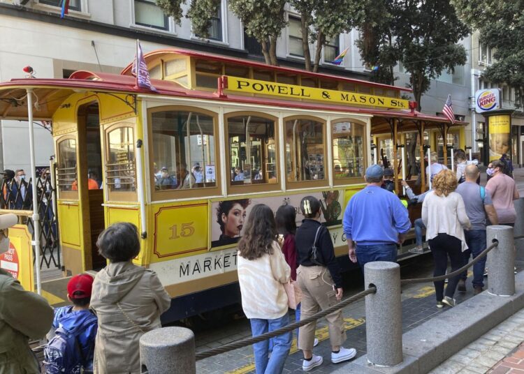 People line up to board a cable car at the Powell Street turnaround plaza in San Francisco on Aug. 2, 2021.