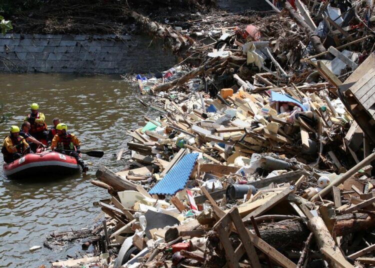 Rescuers and police officers with a dog look for victims in a flood, in Trooz, Belgium, July 20, 2021.