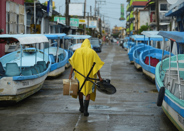A man carries a fan and a box while walking past tourist boats that were moved from the water for safety as Hurricane Grace gathered more strength before reaching land, in Tecolutla, Mexico August 20, 2021.
