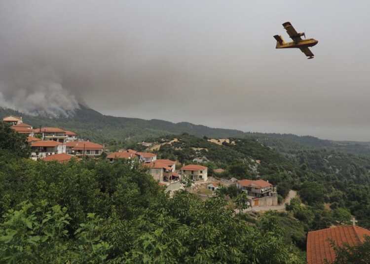 An aircraft operates as flames burn a forest during a wildfire in Kourkouloi village on the island of Evia, about 150 kilometers (93 miles) north of Athens, Greece, Thursday, Aug. 5, 2021. Forest fires fueled by a protracted heat wave raged overnight and into Thursday in Greece, threatening the archaeological site at the birthplace of the modern Olympics and forcing the evacuation of dozens of villages.