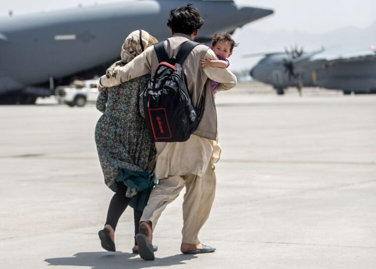 A family walks towards a US Air Force Boeing C-17 Globemaster III during an evacuation at Hamid Karzai International Airport, Afghanistan on August 22, 2021.
