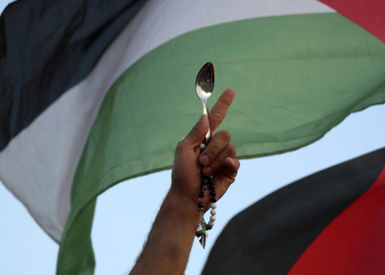 A protester holds a Palestinian flag and a spoon, which has become a symbol celebrating the six Palestinian prisoners who recently tunneled out of Gilboa Prison, in Umm el-Fahm, Israel, Friday, Sept. 10, 2021.