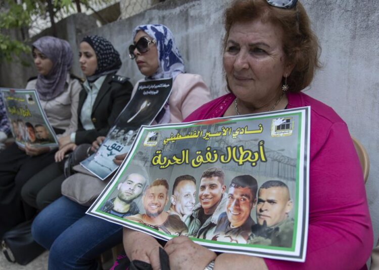 A Palestinian woman carrying a poster with pictures of the six Palestinian prisoners who escaped from an Israeli jail that says "heroes of the freedom tunnel," during a protest in the West Bank city of Ramallah.