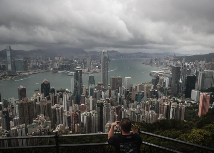 FILE - In this Sept. 1, 2019, file photo, a visitor sets up his camera in the Victoria Peak area to photograph Hong Kong's skyline. Travelers arriving in Hong Kong from China will no longer need to quarantine, Hong Kong’s top official said Tuesday, Sept. 7, 2021, easing curbs imposed after summer outbreaks of the coronavirus on the mainland.