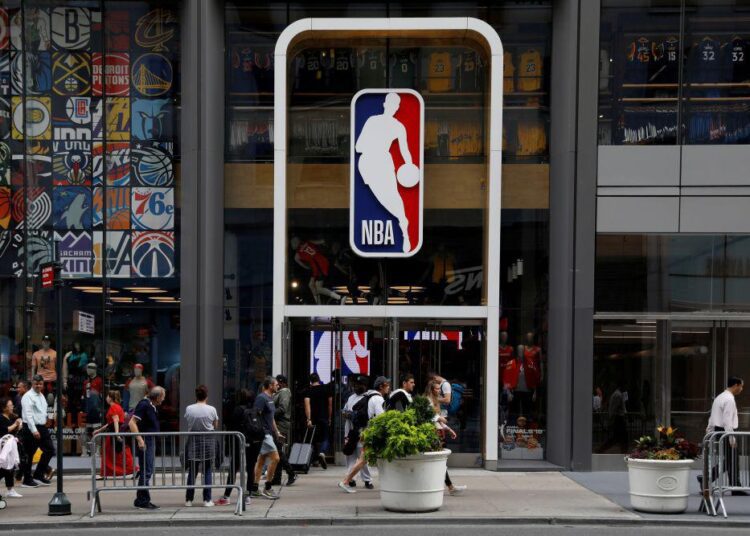 Unvaccinated NBA players to face extensive Covid-19 restrictions 1 - Egyptian Gazette The NBA logo is displayed as people pass by the NBA Store in New York City October 7, 2019.