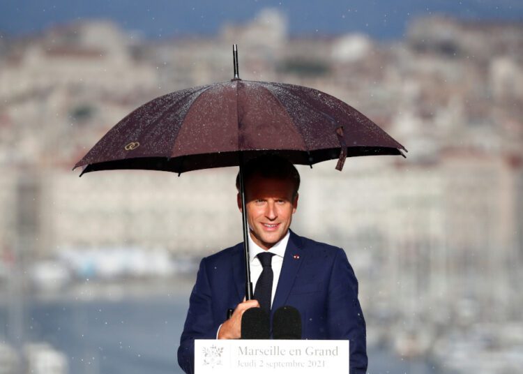 French President Emmanuel Macron holds an umbrella as he delivers a speech at the Palais du Pharo in Marseille, France, September 2, 2021.