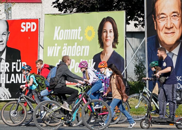 People walk and drive past election posters of the three chancellor candidates, from right, Armin Laschet, Christian Democratic Union (CDU), Annalena Baerbock, German Green party (Die Gruenen) and Olaf Scholz, Social Democratic Party (SPD), at a street in Gelsenkirchen, Germany, on Sept. 23, 2021 three days before the General election on Sunday, Sept. 26, 2021.