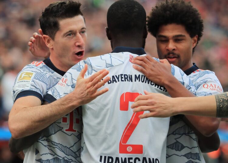 Robert Lewandowski celebrates scoring their first goal with a backheel with Dayot Upamecano and Serge Gnabry.