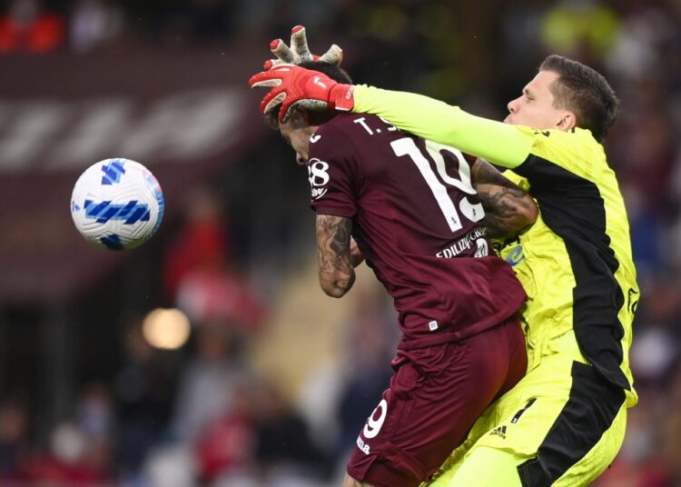 Juventus goalie Wojciech Szczesny and Torino's Antonio Sanabria (L) vie for the ball during their Serie A match at the Turin Olympic stadium.