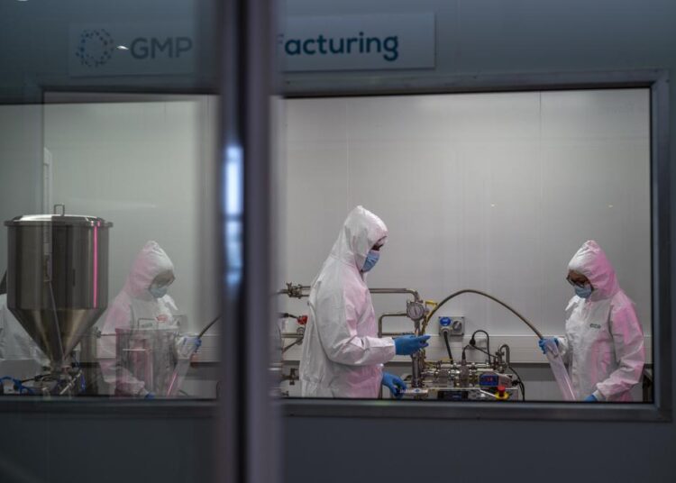 Scientists re-enact the calibration procedure of equipment at an Afrigen Biologics and Vaccines facility in Cape Town, South Africa, Tuesday Oct. 19, 2021. In a pair of warehouses converted into a maze of airlocked sterile rooms, young scientists are assembling and calibrating the equipment needed to reverse engineer a coronavirus vaccine that has yet to reach South Africa and most of the world's poor.