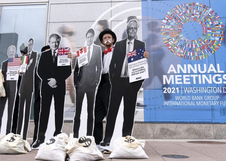 Activists holding a cardboard cutouts of President Joe Biden, Canadian Prime Minister Justin Trudeau, Australian Prime Minister Scott Morrison, Britain's Prime Minister Boris Johnson and Italian Prime Minister Mario Draghi protest outside of the International Monetary Fund headquarters during the World Bank/IMF Annual Meetings in Washington, Wednesday, Oct. 13, 2021.