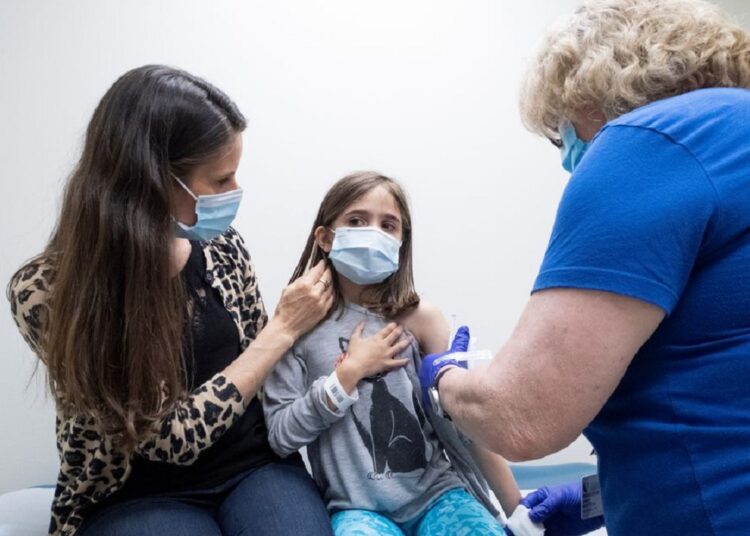 Marisol Gerardo, 9, is held by her mother as she gets the second dose of the Pfizer coronavirus disease (COVID-19) vaccine during a clinical trial for children at Duke Health in Durham, North Carolina, US, April 12, 2021.