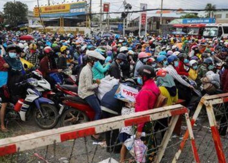 People, mostly migrant workers who are planning to return to their hometowns, wait at a checkpoint to leave Ho Chi Minh City, Vietnam.