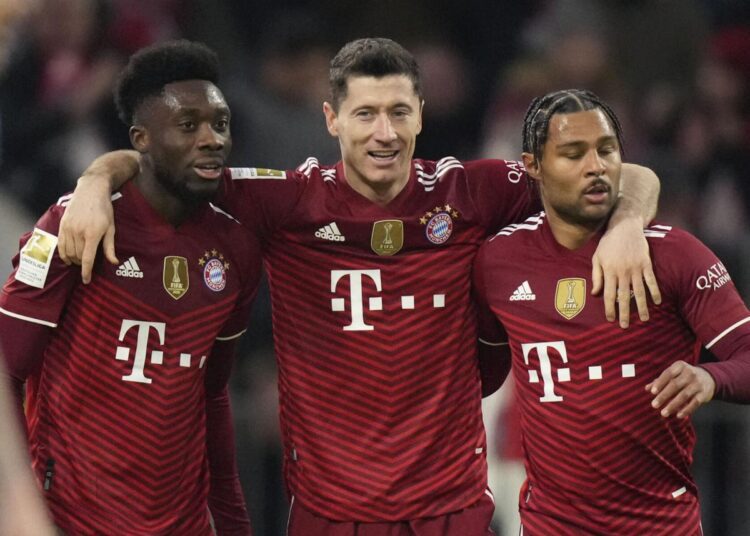 Bayern's Robert Lewandowski (C) celebrates his side's second goal with Bayern's Alphonso Davies (L) and Serge Gnabry during the German Bundesliga match against SC Freiburg in Munich.
