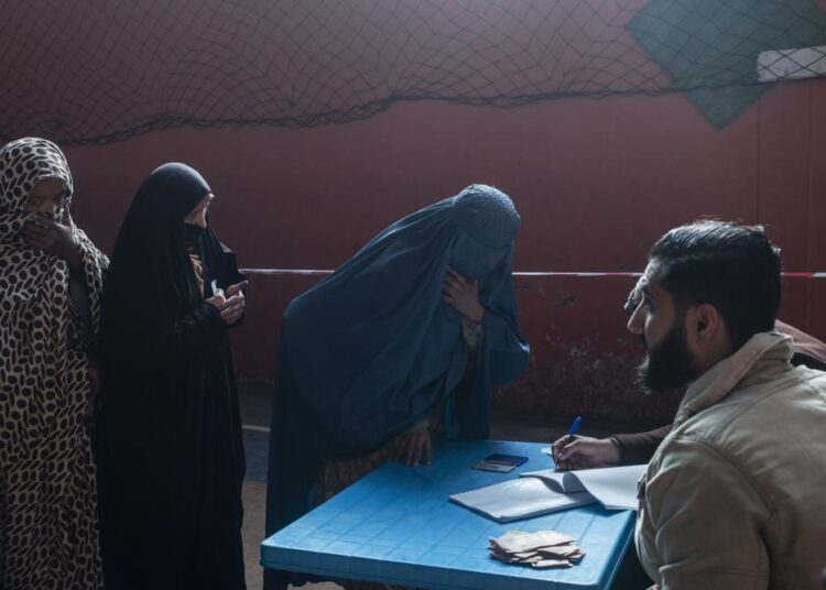 An Afghan woman resisters her name to receive cash at a money distribution center, organized by the World Food Program in Kabul, Afghanistan on Wednesday, Nov. 17, 2021. With the U.N. warning millions are in near-famine conditions, the WFP has dramatically ramped up direct aid to families. (AP Photo/Petros Giannakouris)