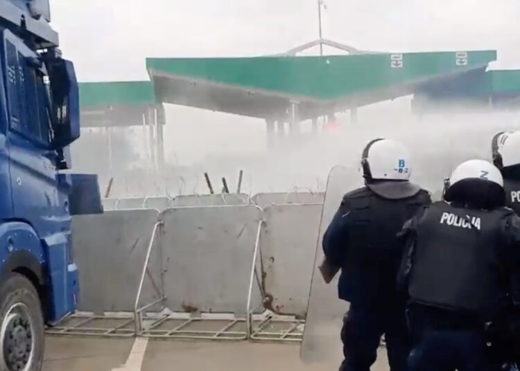A still image, taken from a handout video released by the Polish Defence Ministry, shows Polish law enforcement officers, who stand guard and use a water cannon on migrants at Kuznica - Bruzgi checkpoint on the Polish-Belarusian border, Poland, November 16, 2021. MON/Handout via REUTERS .