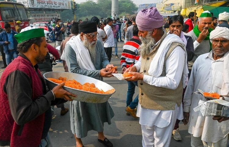 Farmers distribute sweets to celebrate after India's Prime Minister announced to repeal three agricultural reform laws that sparked almost a year of massive protests by farmers around the country in Ghaziabad on November 19.