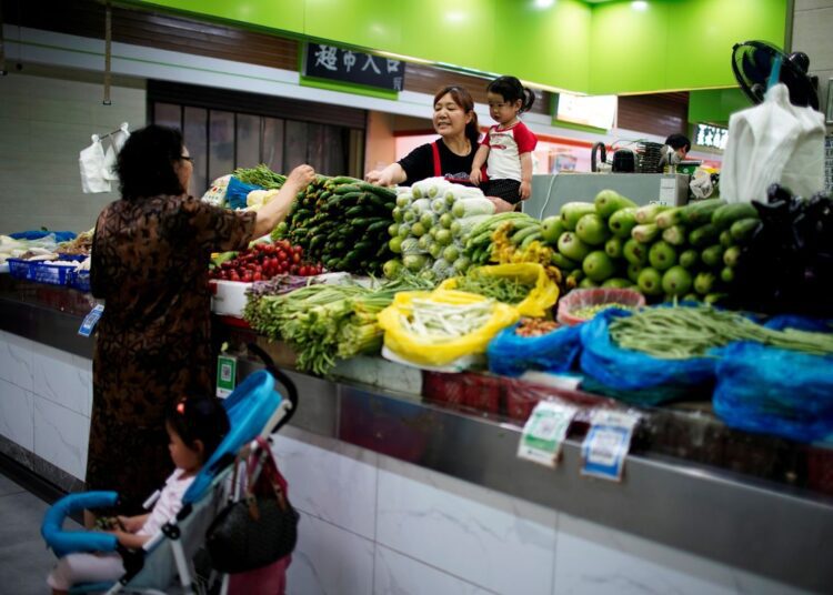 A file photo of two grandmothers with their granddaughters trading vegetables at a market on the outskirts of Shanghai.