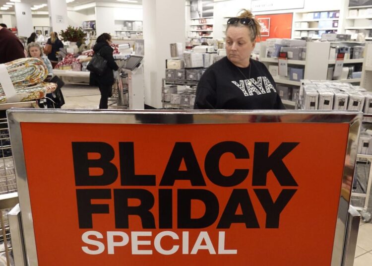 A shopper walks past during a Black Friday sale sign at Macy's, Friday, Nov. 26, 2021, in Indianapolis.