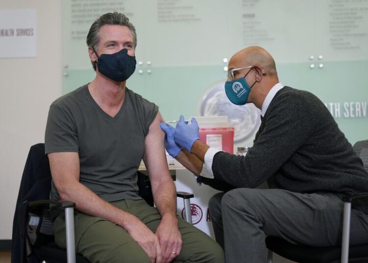 File photo showing California Gov. Gavin Newsom, (L), receiving a Moderna Covid-19 vaccine booster shot from California Health and Human Services Secretary Dr. MarkGhaly at Asian Health Services in Oakland, Calif.