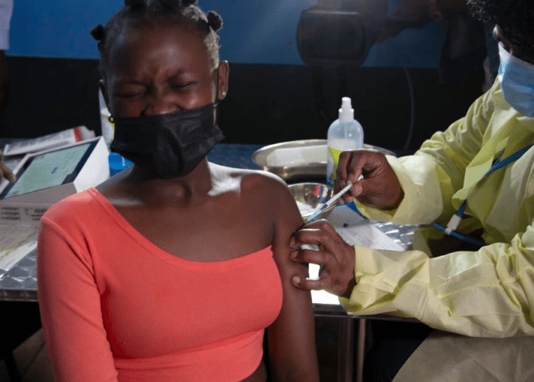 FILE - A young woman reacts as she receives a Pfizer jab against COVID-19, in Diepsloot Township near Johannesburg on Oct. 21, 2021.