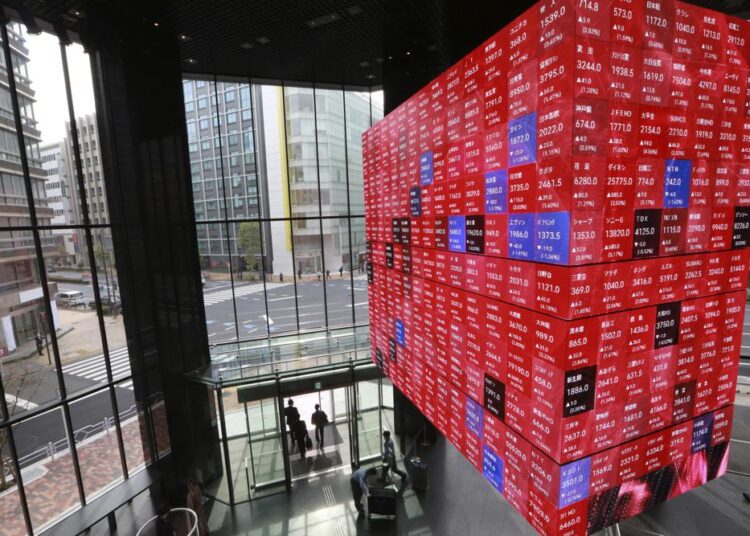 People walking below an electronic stock board at a conference hall in Tokyo Monday, November 1, 2021.
