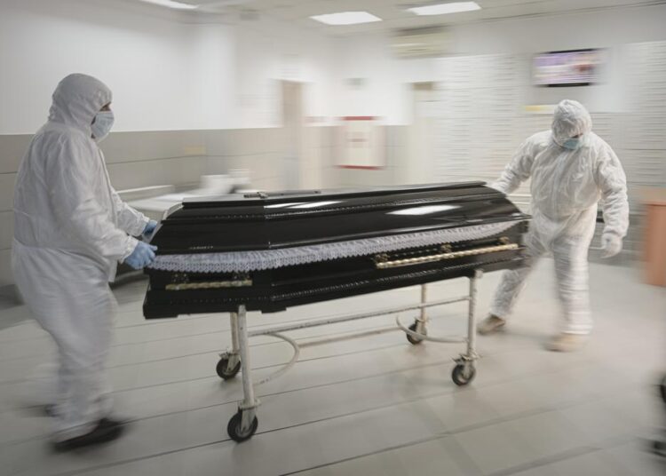 FILE - Funeral house employees drag a coffin on a trolley as they arrive at the University Emergency Hospital morgue to take a COVID-19 victim for burial, in Bucharest, Romania, Monday, Nov. 8, 2021. In much of Eastern Europe, coronavirus deaths are high and vaccination rates are low, but politicians have hesitated to impose the measures curb the virus that experts are calling for. A World Health Organization official declared earlier this month that Europe is again the epicenter of the coronavirus pandemic.